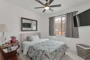 Carpeted bedroom with ceiling fan and baseboards