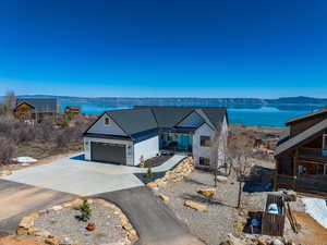 View of front of property with concrete driveway, a garage, and a water view