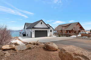 Modern farmhouse with a standing seam roof, metal roof, stone siding, a garage, and concrete driveway