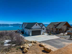 Modern farmhouse with a water view, a standing seam roof, metal roof, a garage, and driveway