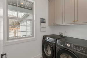 Laundry room with separate washer and dryer, baseboards, and cabinet space