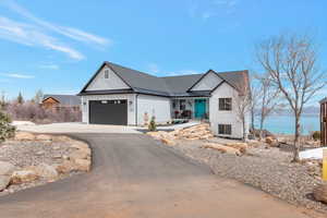View of front of property featuring driveway, an attached garage, metal roof, and a standing seam roof