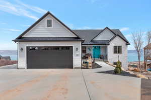 View of front of house featuring concrete driveway, roof with shingles, stone siding, a standing seam roof, and metal roof