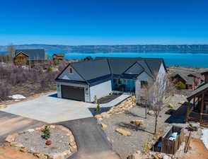 Single story home with a water view, driveway, stone siding, and an attached garage