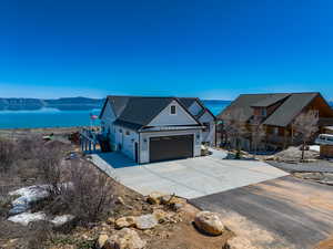 View of front of house with a water view, stone siding, metal roof, a garage, and a standing seam roof
