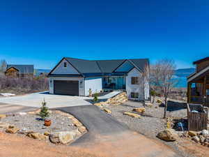 Ranch-style home featuring driveway, an attached garage, stone siding, metal roof, and a standing seam roof