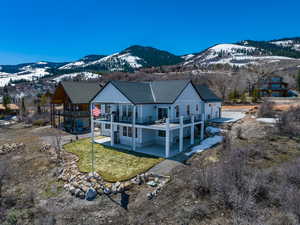 Rear view of house with a patio, a yard, a mountain view, and roof with shingles