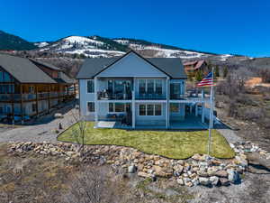 Back of property featuring a patio area, a mountain view, a lawn, and a balcony
