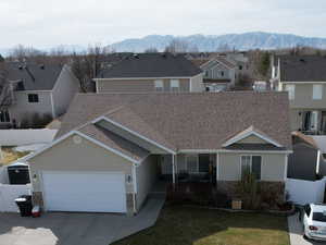 Traditional home featuring an attached garage, fence, a residential view, concrete driveway, and a mountain view