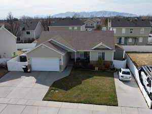 Traditional home featuring an attached garage, fence, a residential view, concrete driveway, and a mountain view