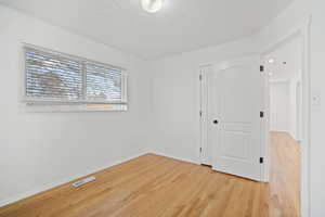 Spare room featuring visible vents, baseboards, and light wood-style floors