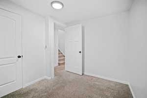 Unfurnished bedroom featuring light carpet and baseboards