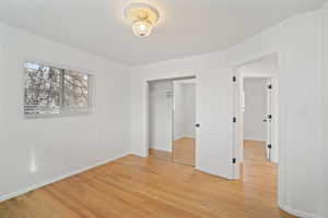 Unfurnished bedroom with a closet, baseboards, and light wood-style flooring