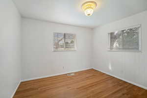 Spare room with wood finished floors, visible vents, and baseboards