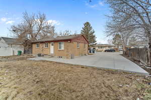 Back of property with brick siding, entry steps, and fence