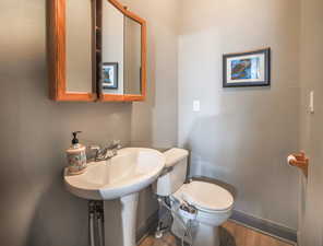 Half bath featuring baseboards, toilet, and wood finished floors