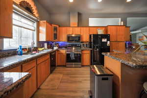 Kitchen with brown cabinetry, black appliances, and a sink