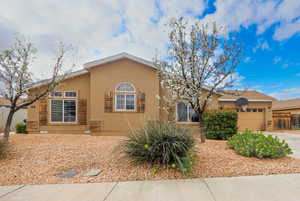 View of front facade featuring stucco siding, a garage, driveway, and fence