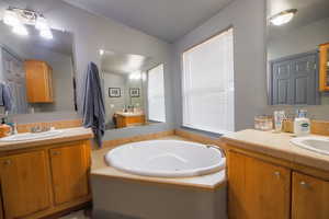 Full bathroom featuring a bath, two vanities, and a sink