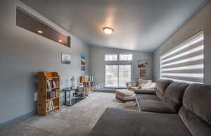 Living area featuring vaulted ceiling and carpet flooring