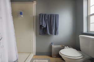 Full bathroom featuring a shower with curtain, tile patterned floors, toilet, and baseboards