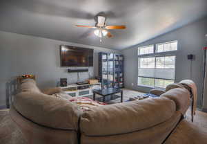 Carpeted living area featuring vaulted ceiling, a ceiling fan, and a wealth of natural light