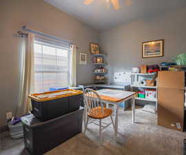 Carpeted home office featuring a ceiling fan