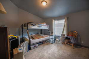 Carpeted bedroom with baseboards and vaulted ceiling