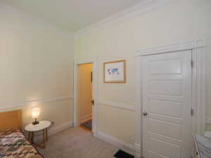 Bedroom with visible vents, baseboards, light colored carpet, and ornamental molding