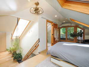 Bedroom with wood finished floors, a skylight, recessed lighting, an AC wall unit, and connected bathroom