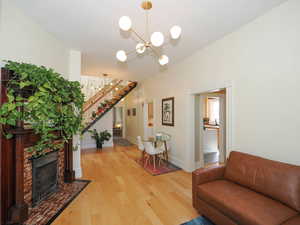 Living area with baseboards, a chandelier, stairway, a tiled fireplace, and light wood-style flooring