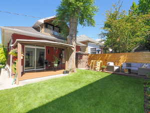 View of yard with an outdoor living space, a balcony, and fence