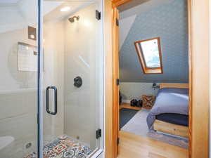 Ensuite bathroom with ensuite bath, wood finished floors, a skylight, a shower stall, and wallpapered walls