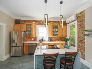 Kitchen featuring brown cabinetry, an AC wall unit, stainless steel appliances, and light countertops