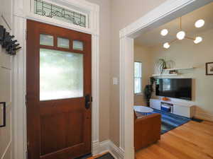 Foyer entrance featuring visible vents, wood finished floors, an inviting chandelier, baseboards, and stairs