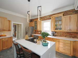 Kitchen featuring a center island, an AC wall unit, light countertops, ornamental molding, and appliances with stainless steel finishes