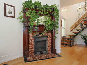 Living room featuring a fireplace, stairway, wood finished floors, and baseboards