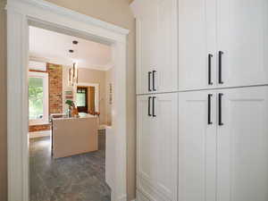 Hall featuring baseboards, brick wall, ornamental molding, a wall mounted air conditioner, and marble finish floor