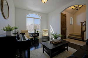 Living room featuring archway, window, wood floors, and chandelier