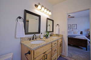 Ensuite bathroom with double vanity, connected bathroom, toilet, and a sink