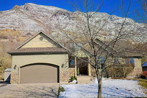 View of front of home featuring concrete driveway, a mountain view, stone siding, and stucco siding