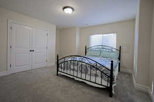 Carpeted bedroom featuring a closet, a textured ceiling, and baseboards