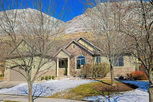 View of front of home with concrete driveway, a mountain view, a garage, and stone siding