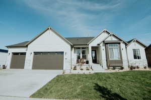View of front of home with driveway, a front lawn, stone siding, board and batten siding, and a garage