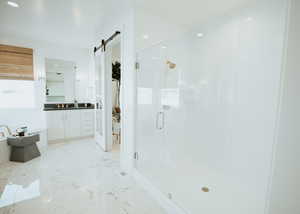Bathroom featuring marble finish floor, a stall shower, and vanity