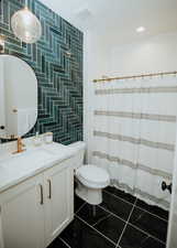 Full bathroom with visible vents, toilet, vanity, a shower with shower curtain, and tile walls