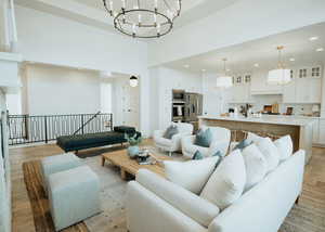 Living room featuring a notable chandelier, recessed lighting, light wood finished floors, and a towering ceiling