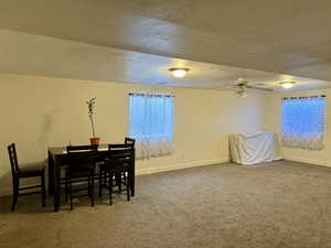 Carpeted dining area featuring a ceiling fan, baseboards, and a textured ceiling