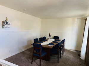 Carpeted dining space featuring a wainscoted wall and a textured ceiling