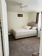 Carpeted bedroom with baseboards, a textured ceiling, and a ceiling fan